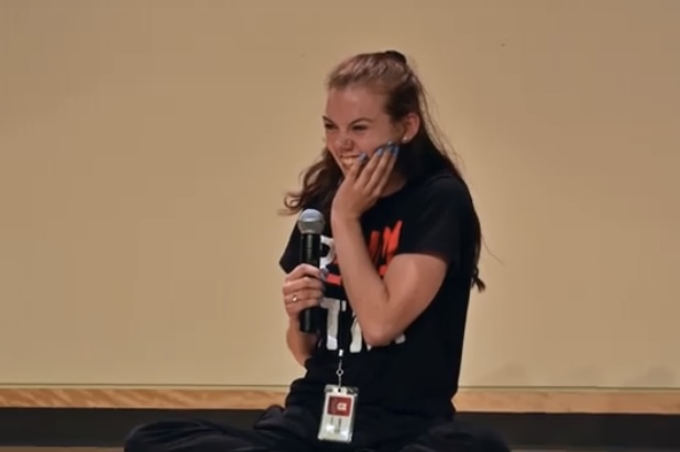 Maria Feider speaking into a microphone during a youth leadership event