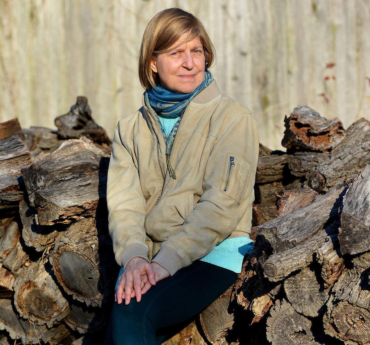 Elizabeth Kipp outdoors beside a woodpile.