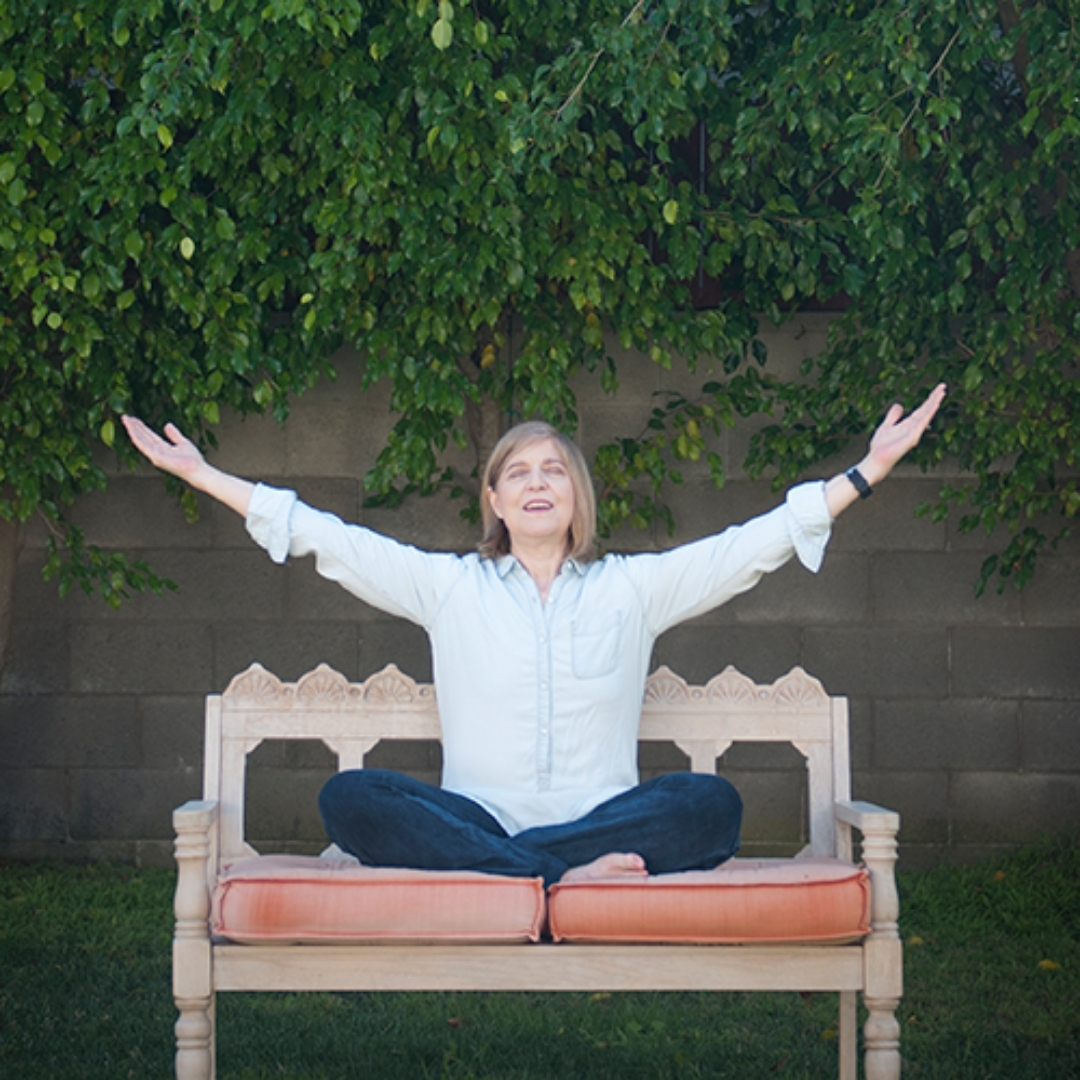 Elizabeth Kipp outdoors in nature with her arms raised in gratitude.